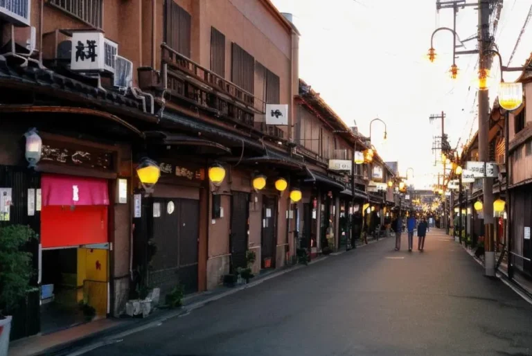 A picturesque view of a traditional Japanese street in Kyoto, featuring wooden buildings with illuminated lanterns and few pedestrians, created using Stable Diffusion.