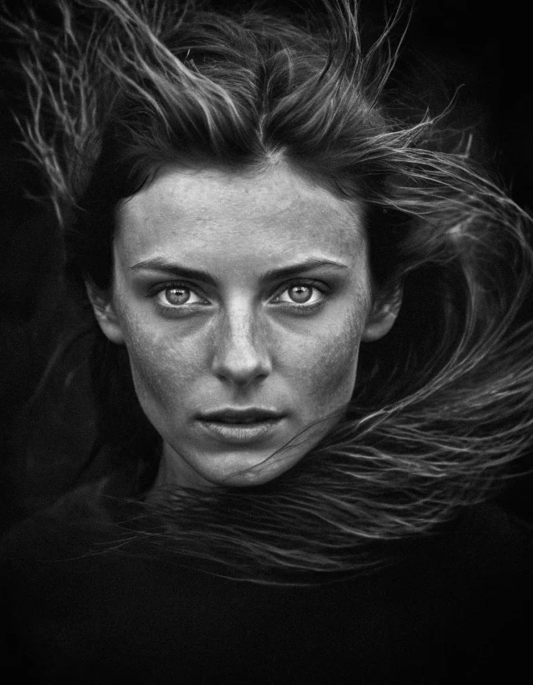 A black and white portrait of a woman with an intense gaze, hair flowing around her face, generated using Stable Diffusion.